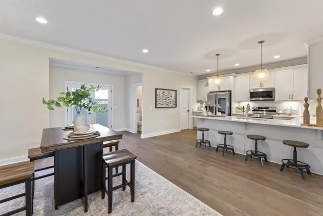 a kitchen with stainless steel appliances kitchen island granite countertop a table chairs and a refrigerator