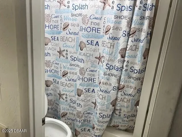 a bathroom with a toilet and a shower curtain