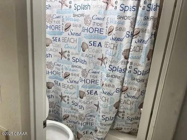 a bathroom with a toilet and a shower curtain