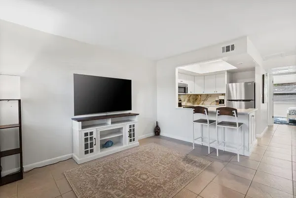a living room with stainless steel appliances furniture a dining table and chairs