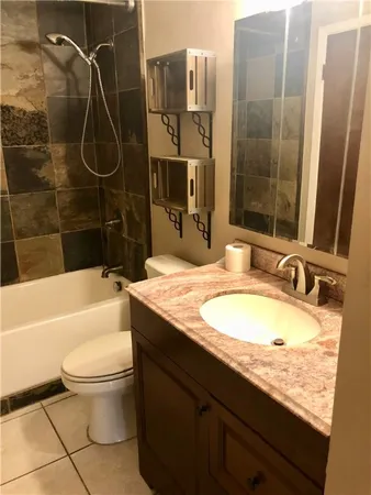 a bathroom with a granite countertop toilet sink and mirror