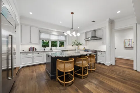 a kitchen with stainless steel appliances kitchen island granite countertop a dining table chairs and granite counter tops