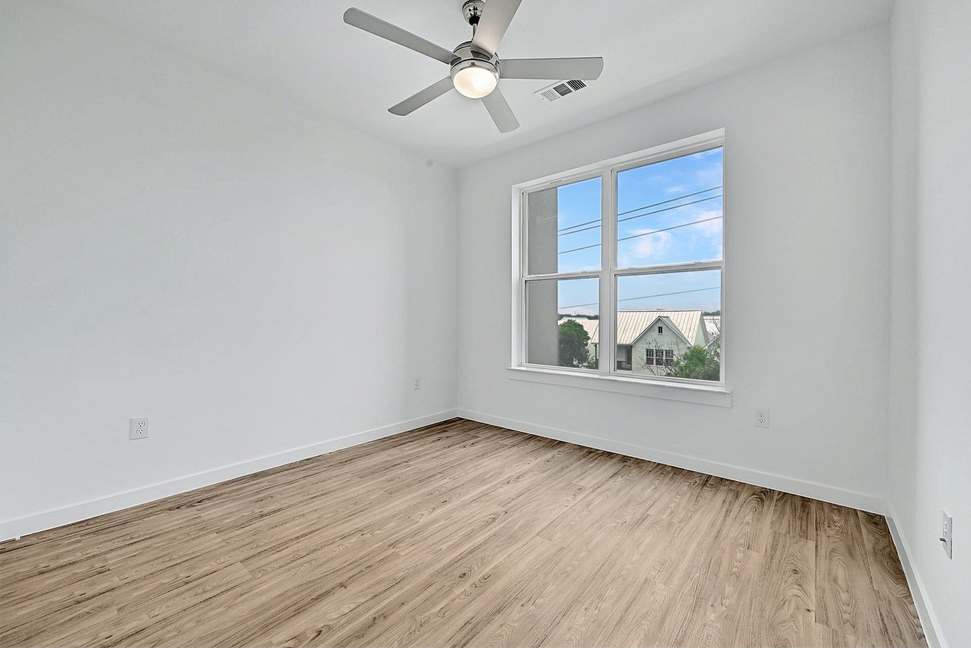 4801 Springdale Road, Unit 1301 Austin, TX 78723 - Photo 19 of 39 A quiet bedroom with light wood flooring and a modern ceiling fan, ready for personal touches.