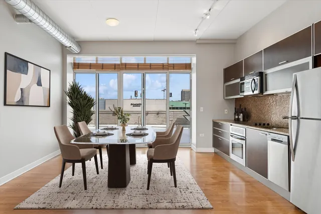 a kitchen with a refrigerator a stove and a dining table with wooden floor