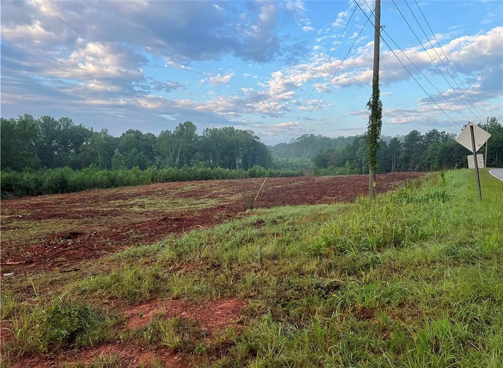 Lot 11 Pickens Drive Pendleton, SC 29670 - Photo 4 of 9 Expansive cleared lot awaits your vision, surrounded by mature trees under an open sky.