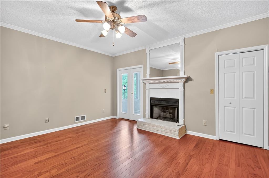 2197 Spring Walk Court Atlanta, GA 30341 - Photo 11 of 31 an empty room with wooden floor a chandelier fan and a fireplace