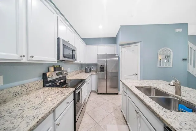 a room with kitchen island stainless steel appliances a sink and a counter top space