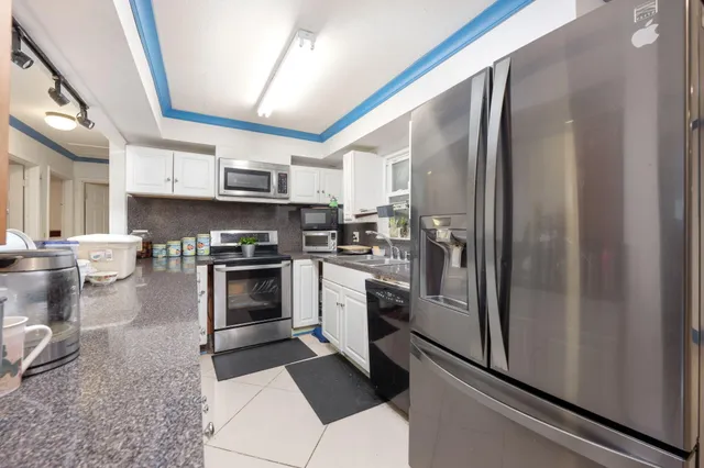 a kitchen with stainless steel appliances granite countertop a refrigerator a stove and a sink