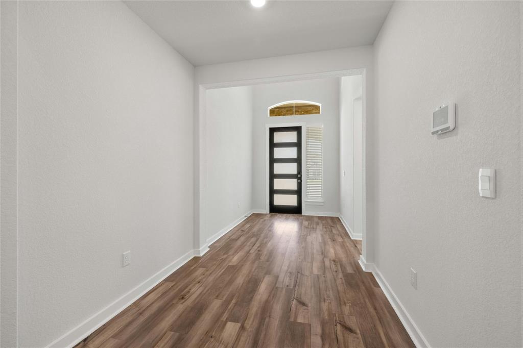 113 Shadow Oak Cove Georgetown, TX 78628 - Photo 15 of 40 Natural light filters through the arched transom window, illuminating the entryway's rich wood flooring.