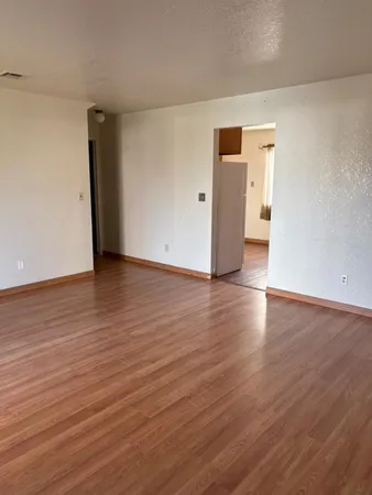 a view of an empty room with wooden floor and closet