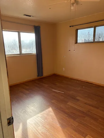 an empty room with wooden floor and windows