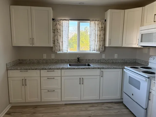 a kitchen with granite countertop white cabinets stainless steel appliances a sink and a window