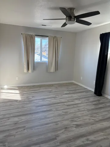 a view of an empty room with wooden floor and a window