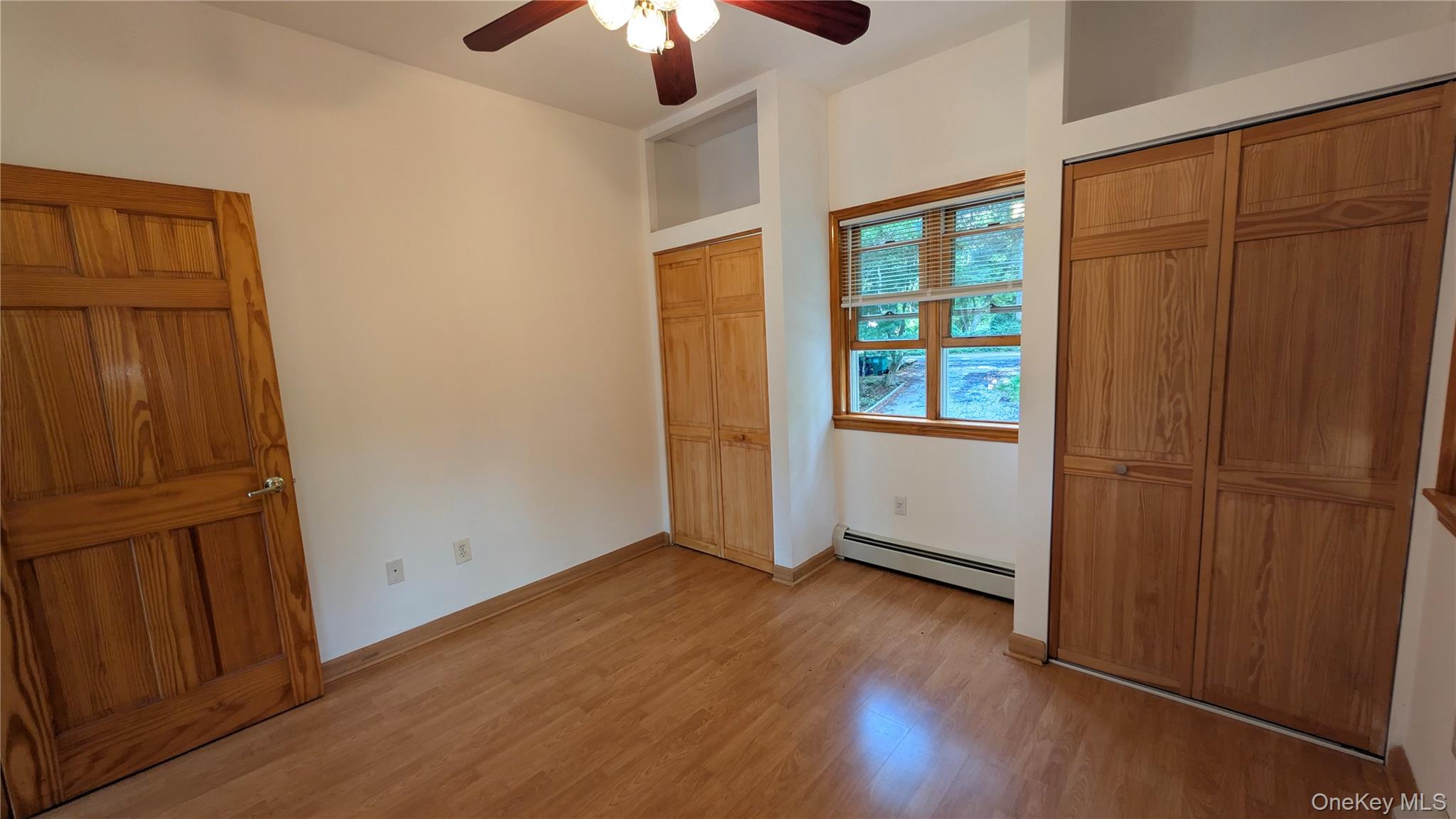 169 Shear Hill Road Mahopac, NY 10541 - Photo 20 of 31 Unfurnished bedroom featuring multiple closets, light wood-style floors, baseboard heating, and ceiling fan