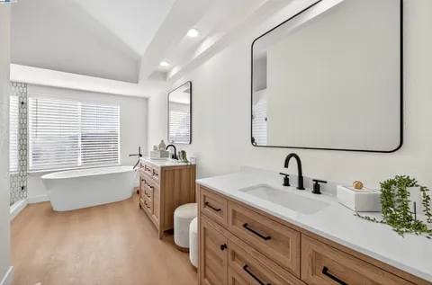 a bathroom with a sink a bathtub a mirror and vanity