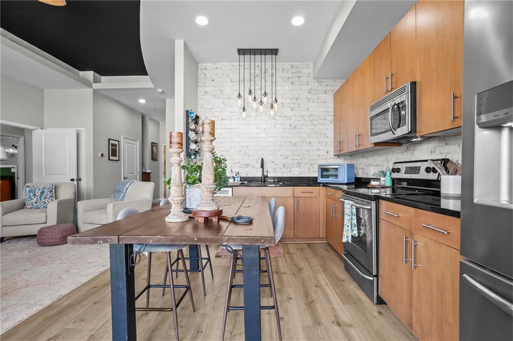 3400 Malone Drive, Unit 219 Atlanta, GA 30341 - Photo 19 of 60 a kitchen with stainless steel appliances kitchen island granite countertop a table chairs in it and wooden floors
