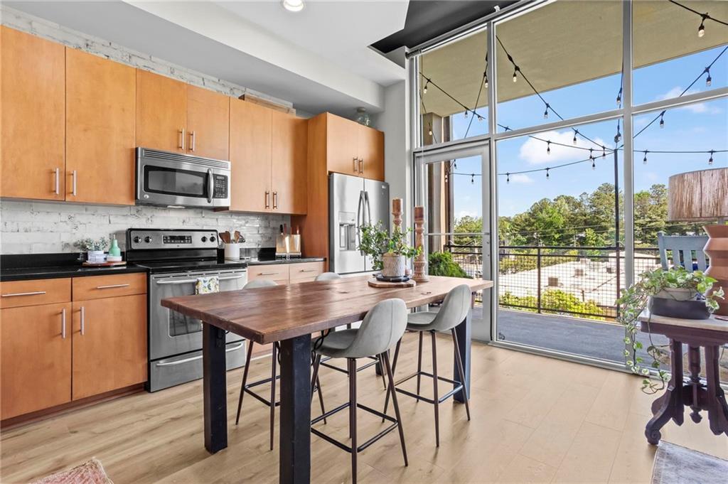 3400 Malone Drive, Unit 219 Atlanta, GA 30341 - Photo 4 of 60 a kitchen with stainless steel appliances granite countertop a stove a refrigerator a microwave oven with a dining table and chairs with wooden floor