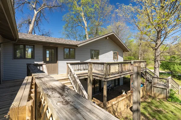 a view of a house with a wooden deck and a barbeque