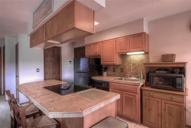 a kitchen with stainless steel appliances kitchen island granite countertop a sink refrigerator stove and microwave