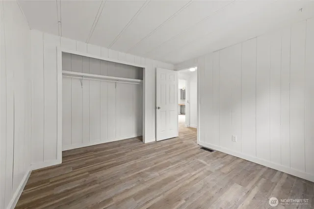 a view of an empty room with wooden floor and closet