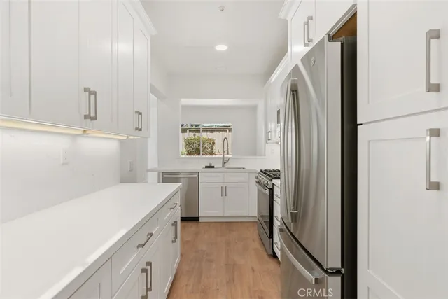 a view of a kitchen with white cabinets and wooden floor