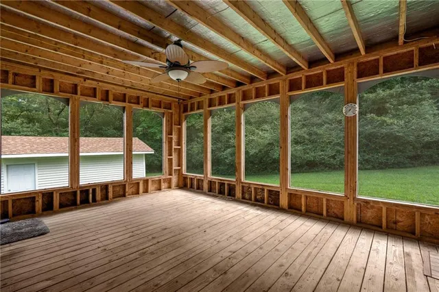 a view of an empty room with window a ceiling fan and wooden floor