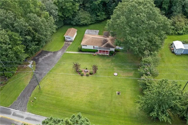an aerial view of a residential houses with outdoor space and trees