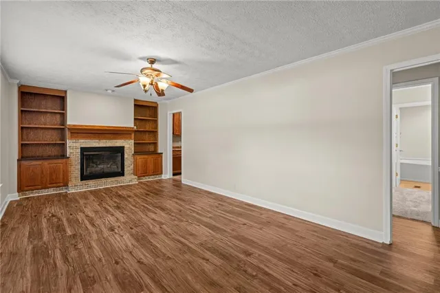 an empty room with wooden floor chandelier fan and windows