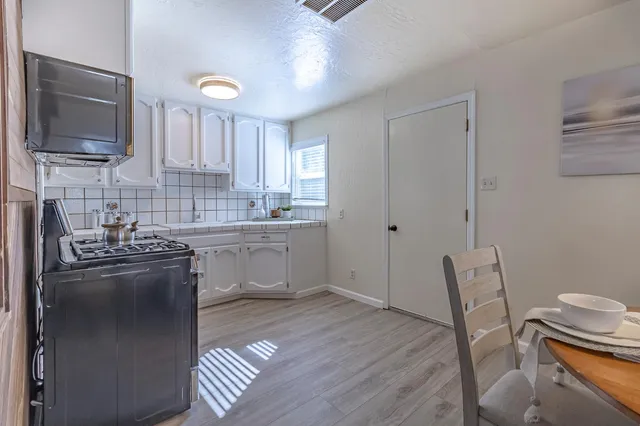 a kitchen with stainless steel appliances granite countertop a stove a sink dishwasher a microwave oven and a refrigerator with wooden floor