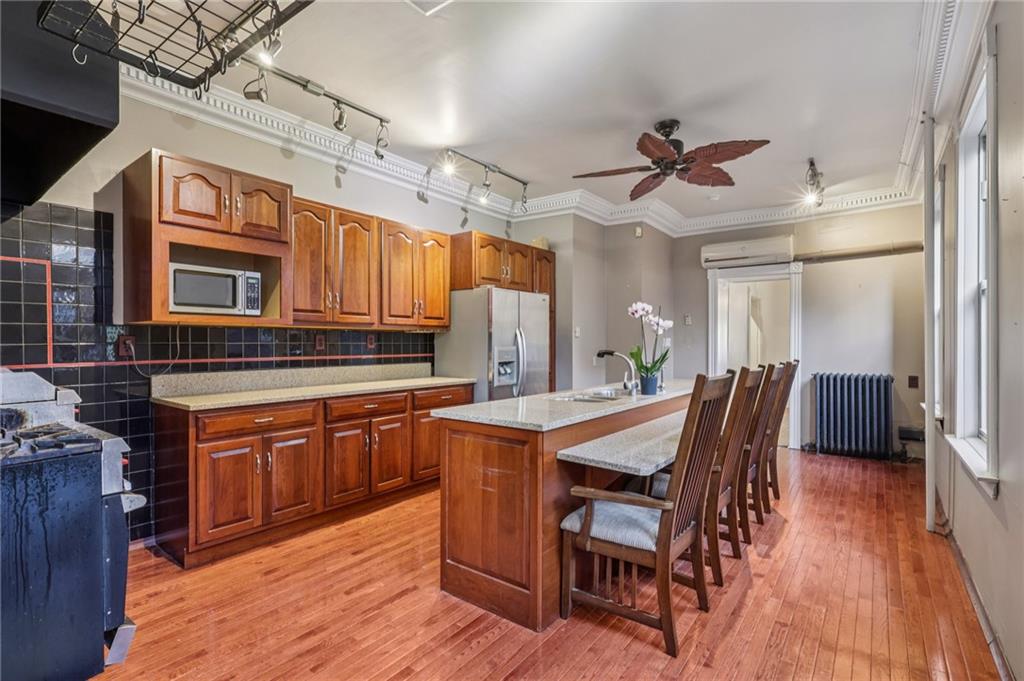 1218 Sherman Avenue Pittsburgh, PA 15212 - Photo 18 of 48 a dining hall with stainless steel appliances granite countertop a stove a sink dishwasher and a dining table with wooden floor