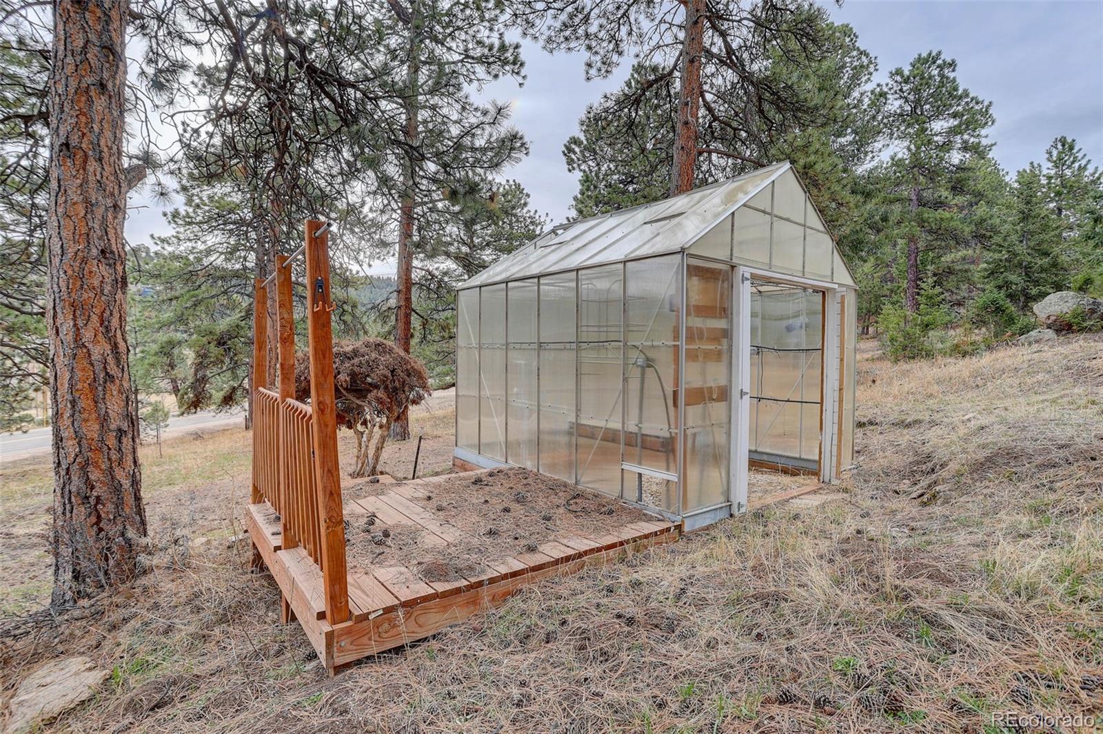 27857 Apex Circle Evergreen, CO 80439 - Photo 28 of 37 a view of a tiny house with large trees and a wooden fence