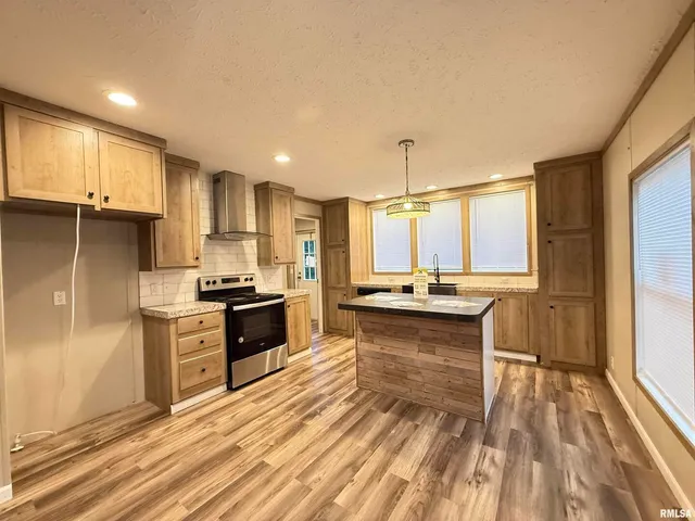 a kitchen with kitchen island granite countertop a sink stove and refrigerator