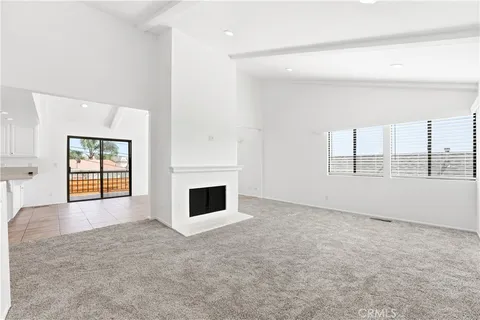 an empty room with windows and fireplace