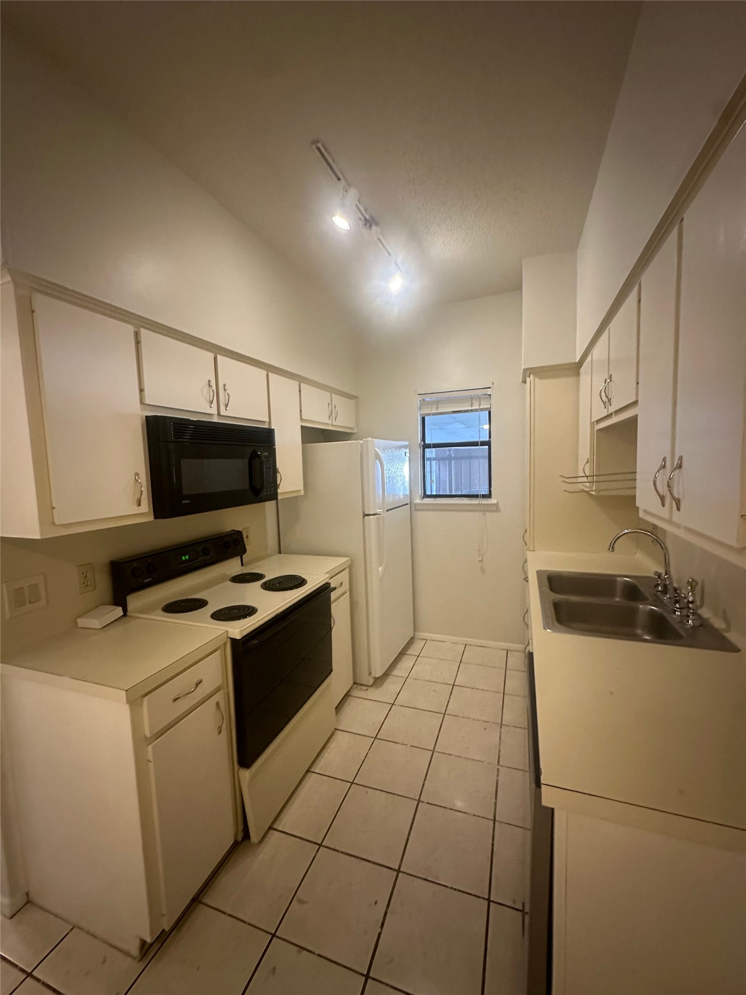 106 East 30th Street, Unit 101 Austin, TX 78705 - Photo 6 of 11 Kitchen featuring electric range, white cabinets, black microwave, light countertops, and rail lighting