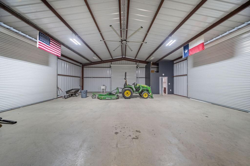 1161 Alsdorf Road Ennis, TX 75119 - Photo 21 of 28 Spacious metal building with a high vaulted ceiling, exposed metal beams, concrete flooring, and multiple large roll-up doors