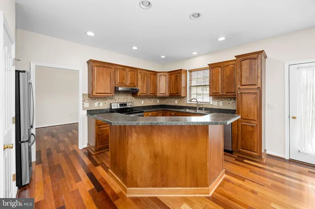 a kitchen with stainless steel appliances granite countertop a refrigerator a stove top oven and a sink