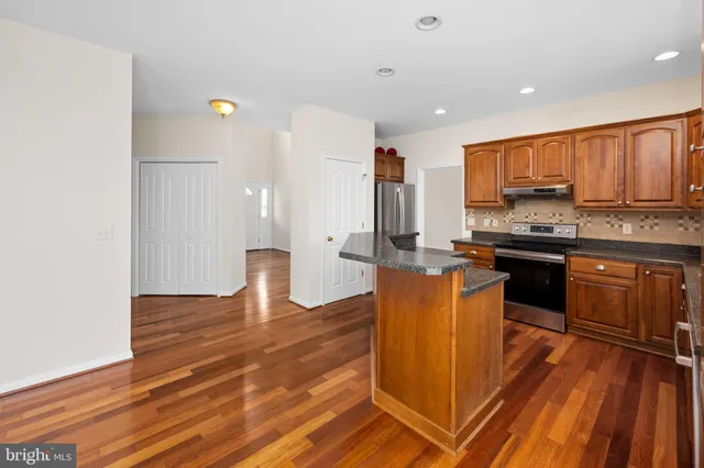 a kitchen with stainless steel appliances granite countertop a sink a stove and a refrigerator