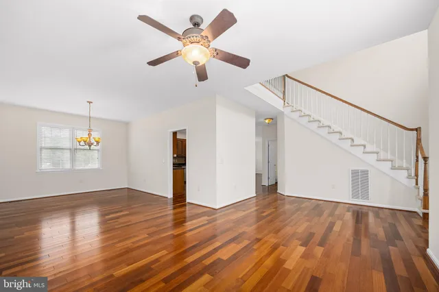 a view of empty room with wooden floor and ceiling fan