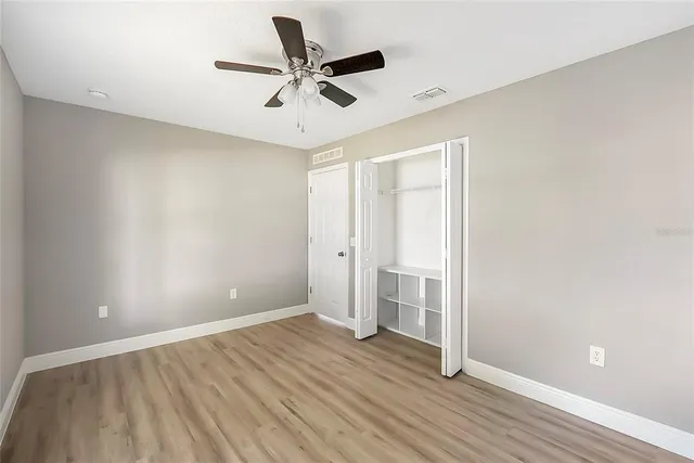 an empty room with a ceiling fan and wooden floor