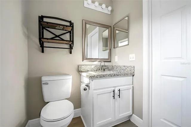 a bathroom with a granite countertop toilet sink and mirror