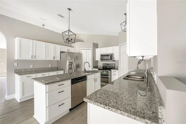 a kitchen with stainless steel appliances granite countertop a sink stove and refrigerator