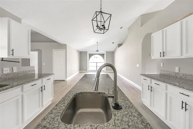 a kitchen with granite countertop a sink a counter top space and cabinets