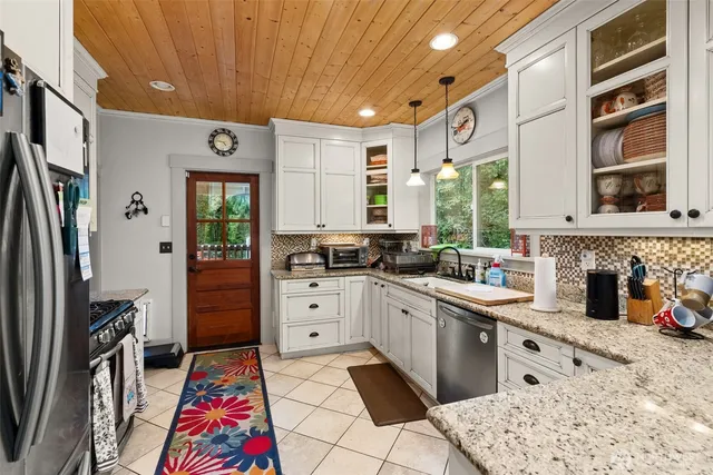 a very nice looking open kitchen with stainless steel appliances granite countertop a sink stove and refrigerator