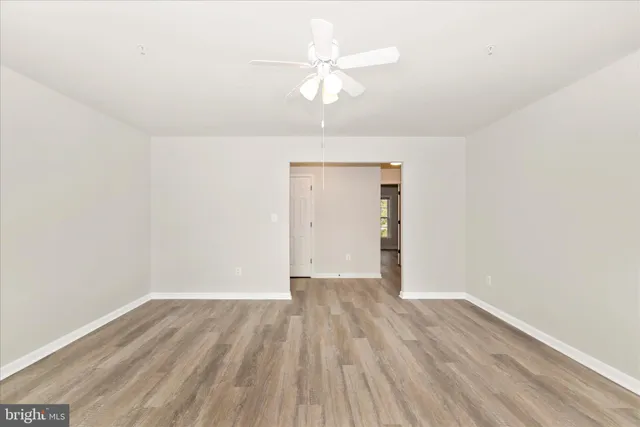 an empty room with wooden floor and ceiling fan