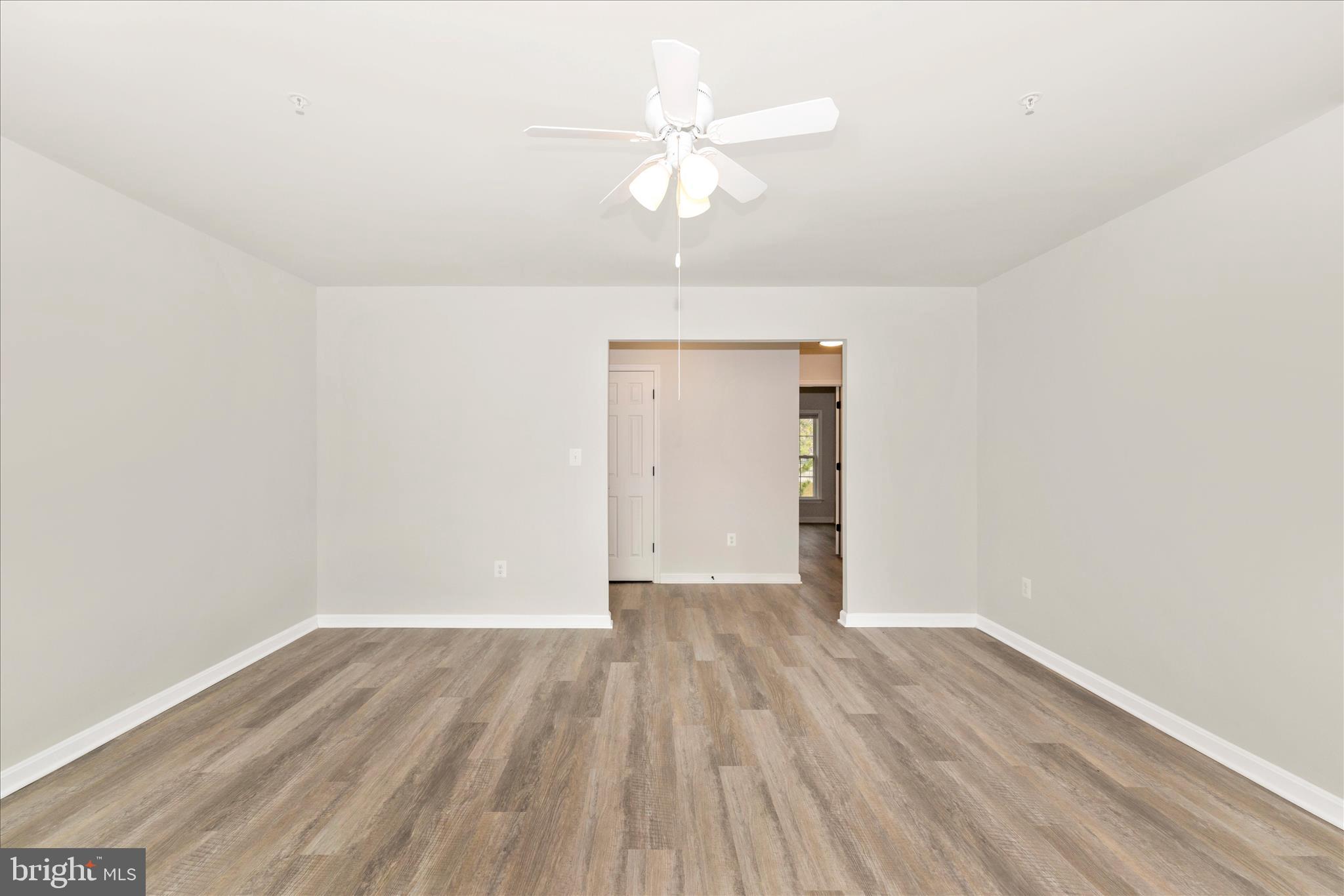 828 Quince Orchard Boulevard, Unit 82820 Gaithersburg, MD 20878 - Photo 14 of 51 an empty room with wooden floor chandelier fan and closet area