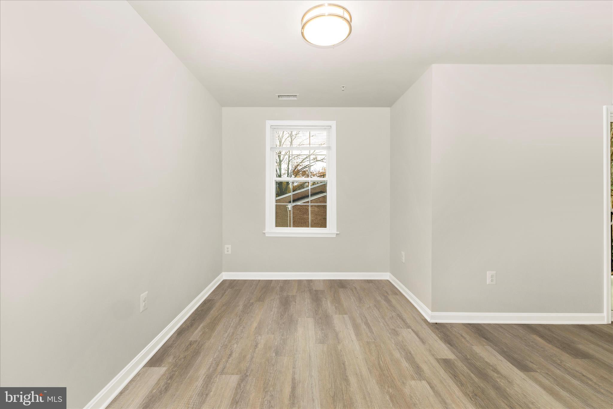828 Quince Orchard Boulevard, Unit 82820 Gaithersburg, MD 20878 - Photo 22 of 51 an empty room with wooden floor and windows