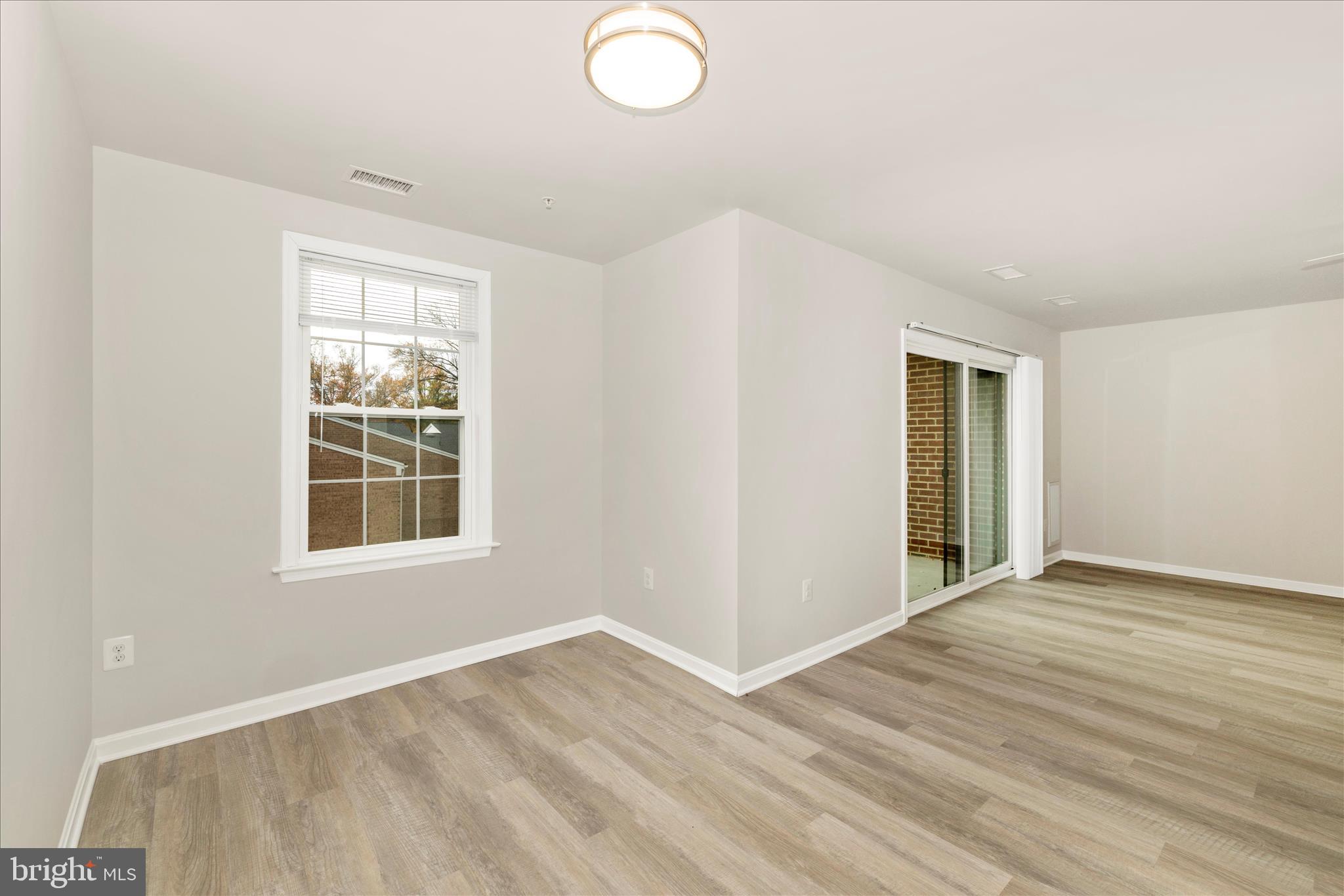 828 Quince Orchard Boulevard, Unit 82820 Gaithersburg, MD 20878 - Photo 23 of 51 an empty room with wooden floor and windows