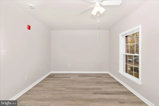 an empty room with wooden floor and ceiling fan
