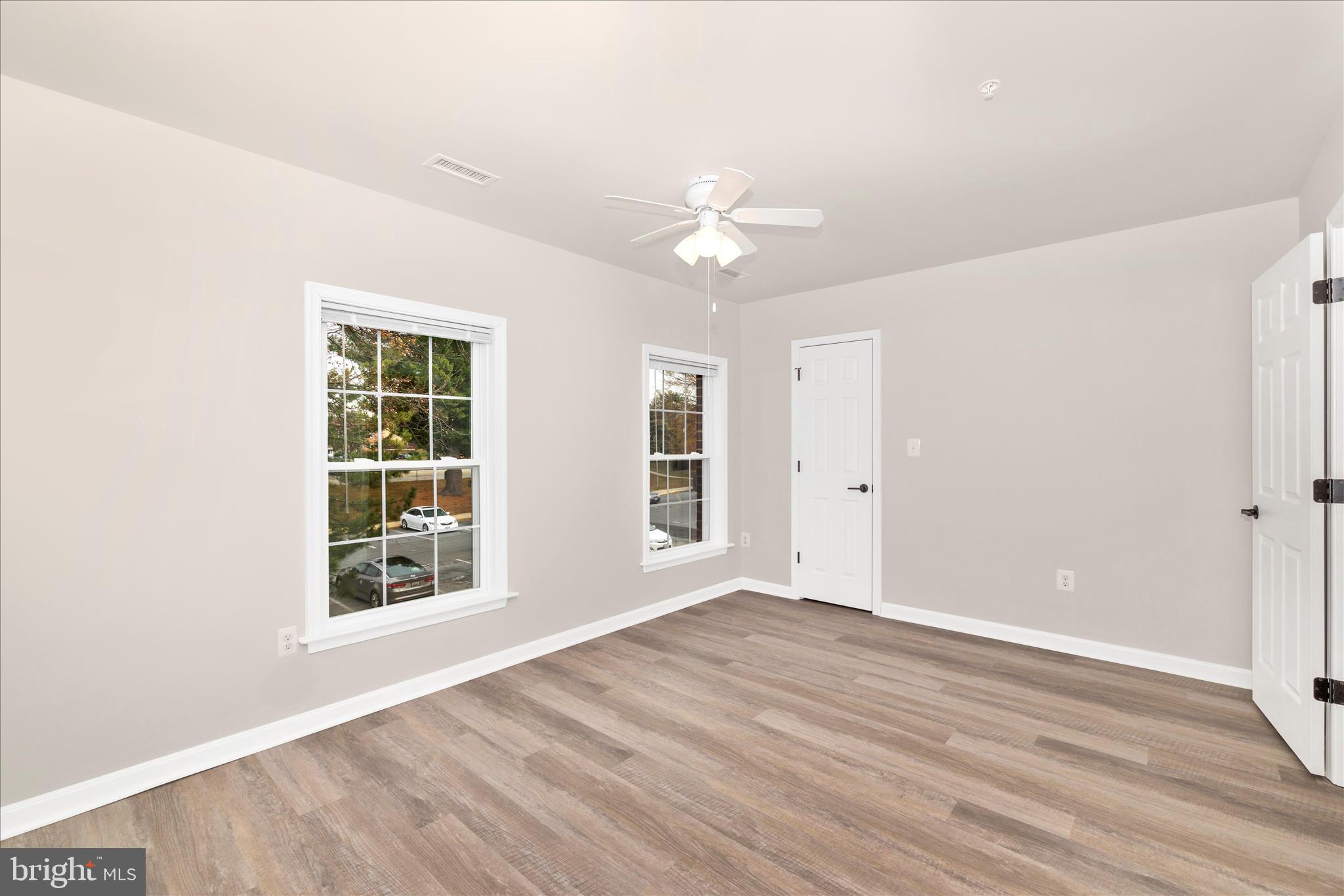 828 Quince Orchard Boulevard, Unit 82820 Gaithersburg, MD 20878 - Photo 38 of 51 an empty room with wooden floor chandelier fan and windows