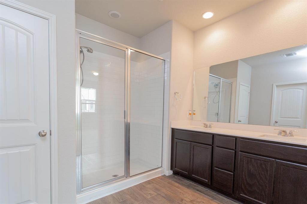 14614 Frankel Loop Pflugerville, TX 78660 - Photo 7 of 15 A well-appointed primary bathroom featuring a spacious shower and a wide vanity with dual sinks.